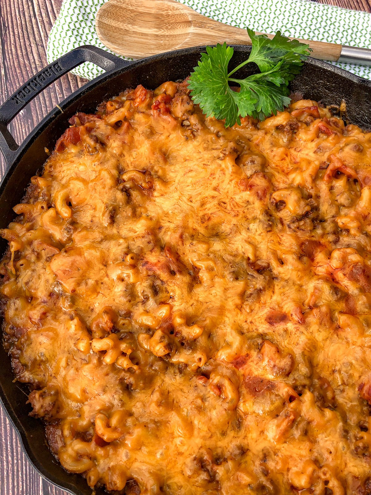 Bacon cheeseburger casserole baked in a cast iron skillet with melted cheddar on top.