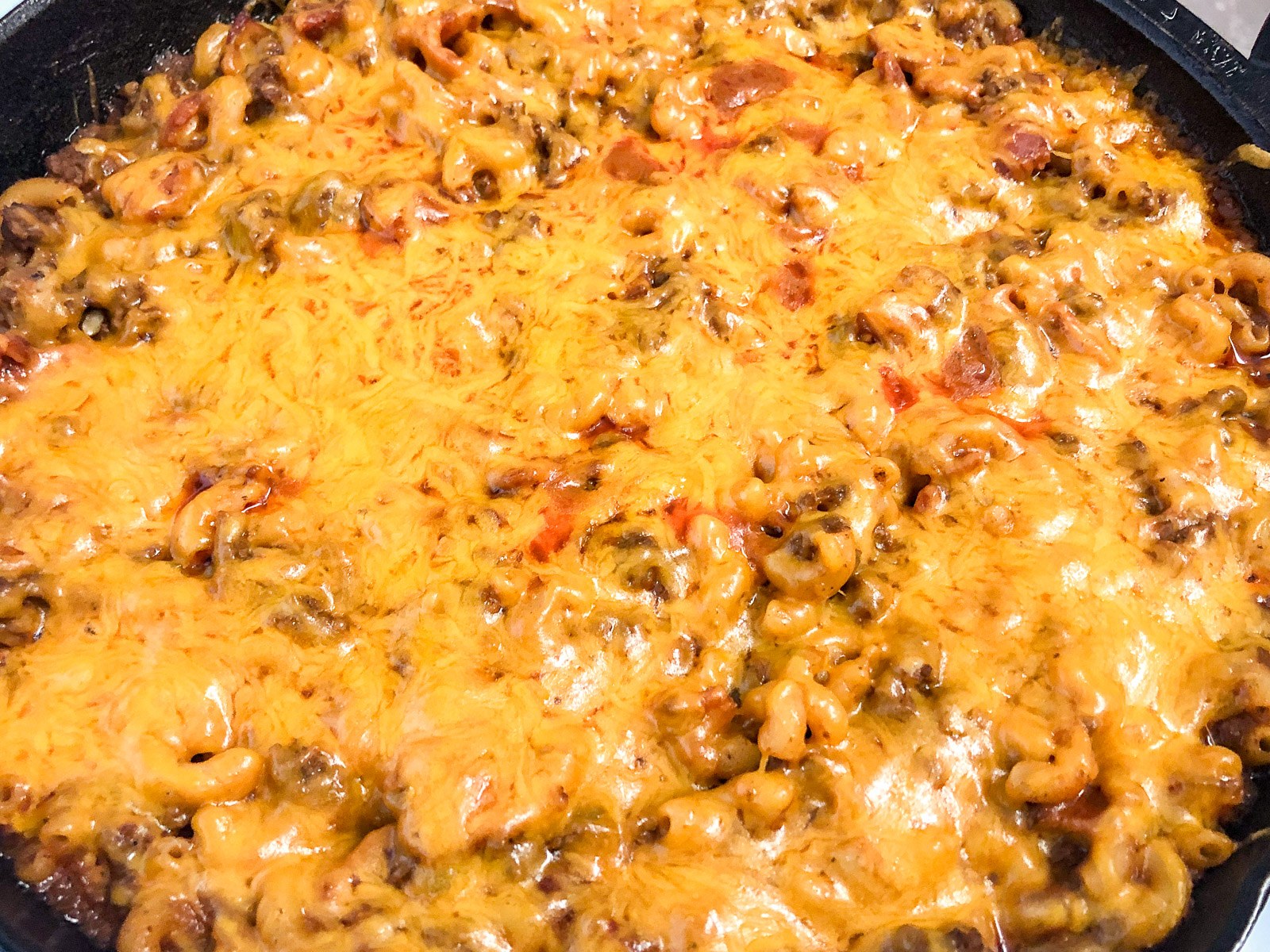 Shredded cheddar cheese melted over the cheeseburger casserole.