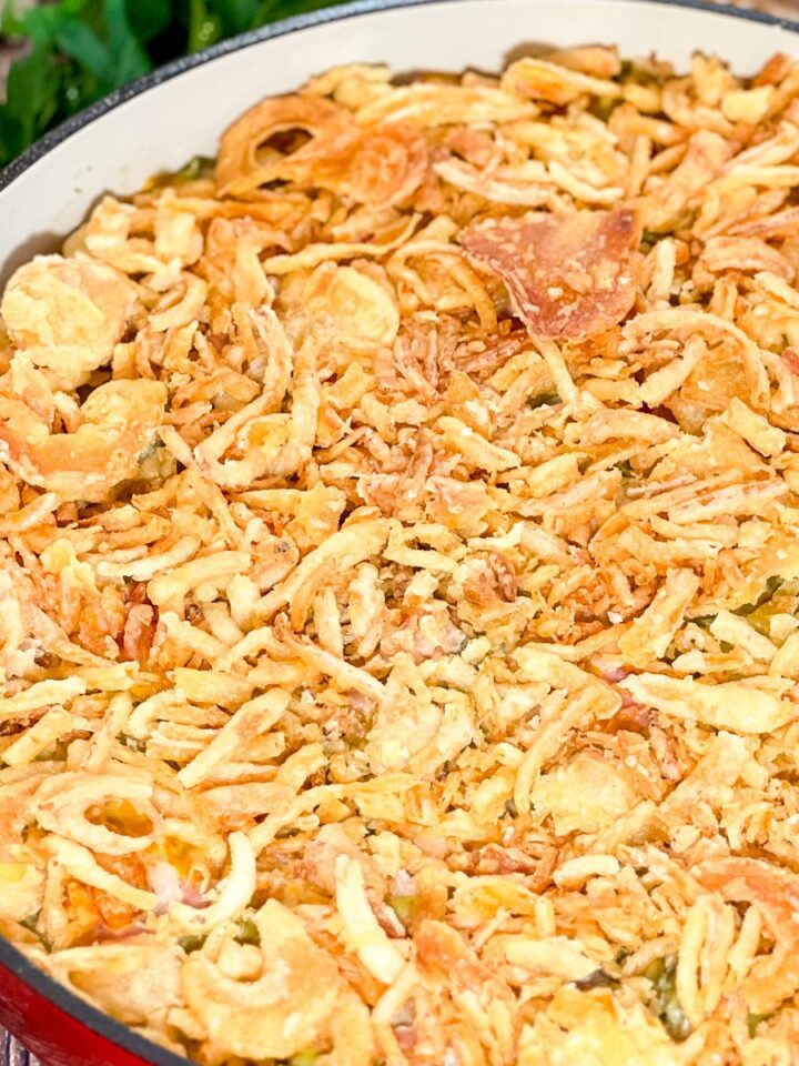 Bacon green bean casserole topped with golden French fried onions in a cast iron Dutch oven.