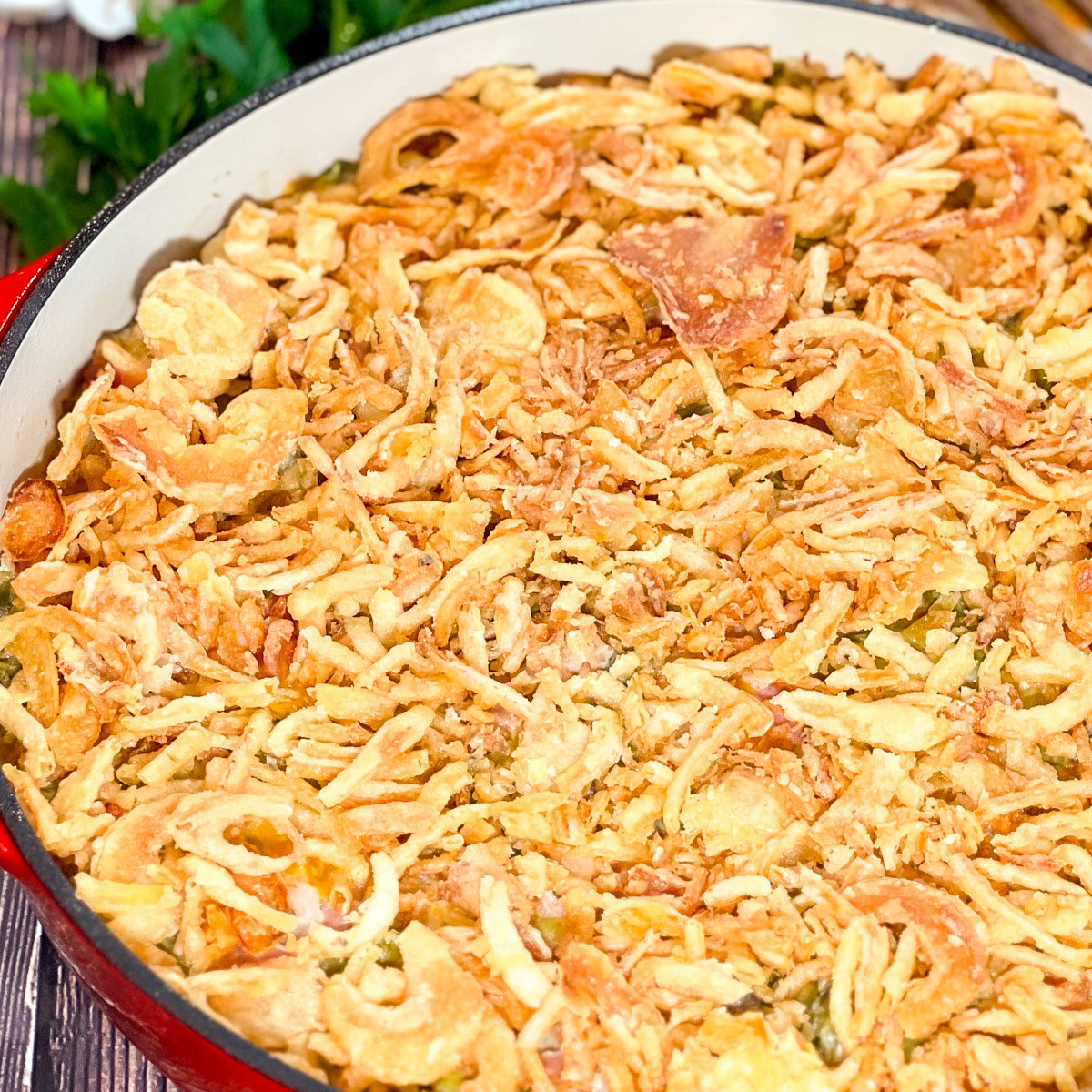 Bacon green bean casserole topped with golden French fried onions in a cast iron Dutch oven.