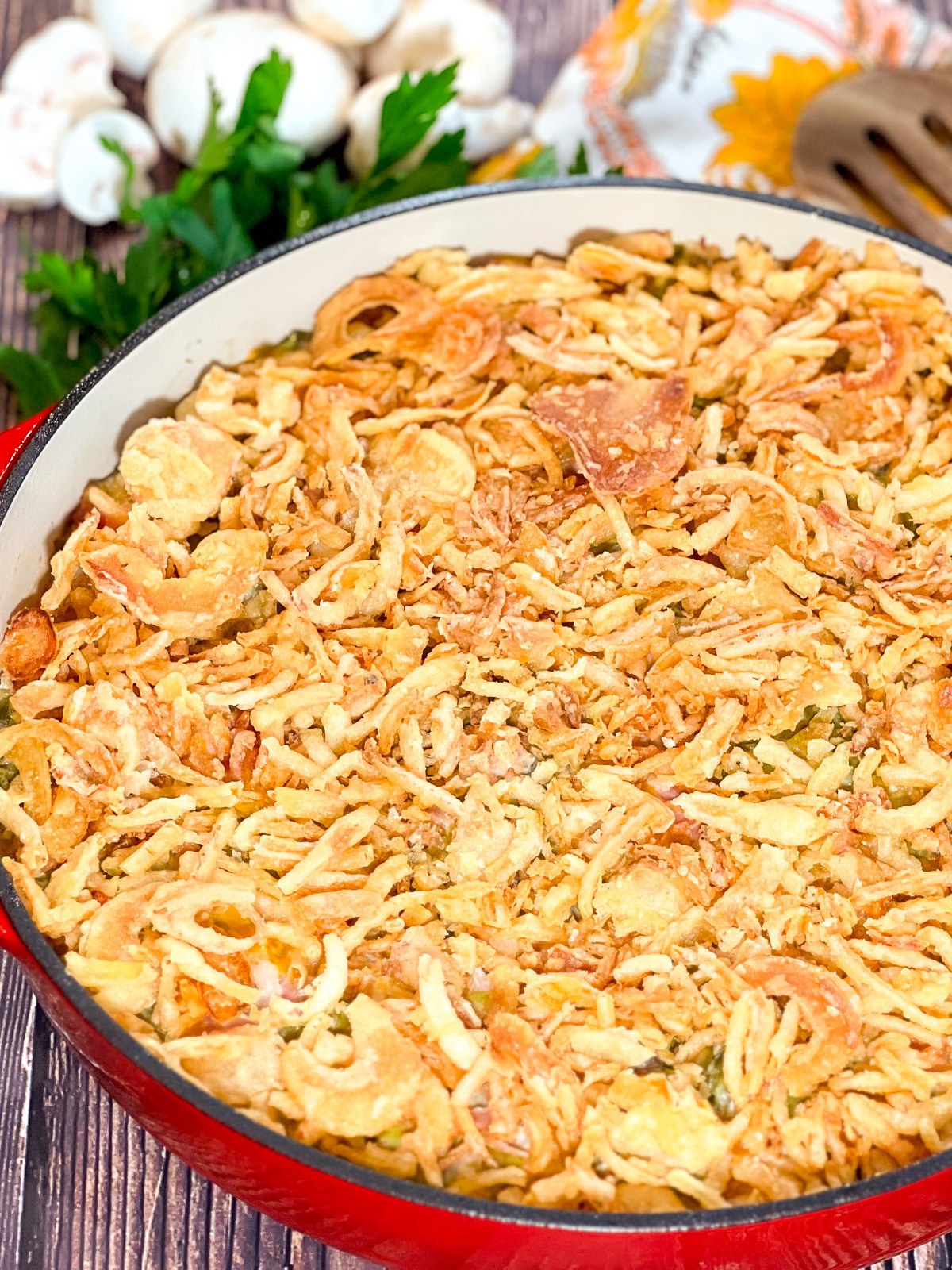 Cheesy green bean casserole with bacon baked in a red cast iron Dutch oven.