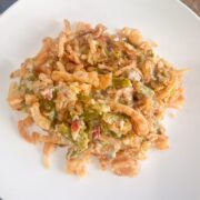 A plated serving of green bean casserole with bacon and crispy fried onions.