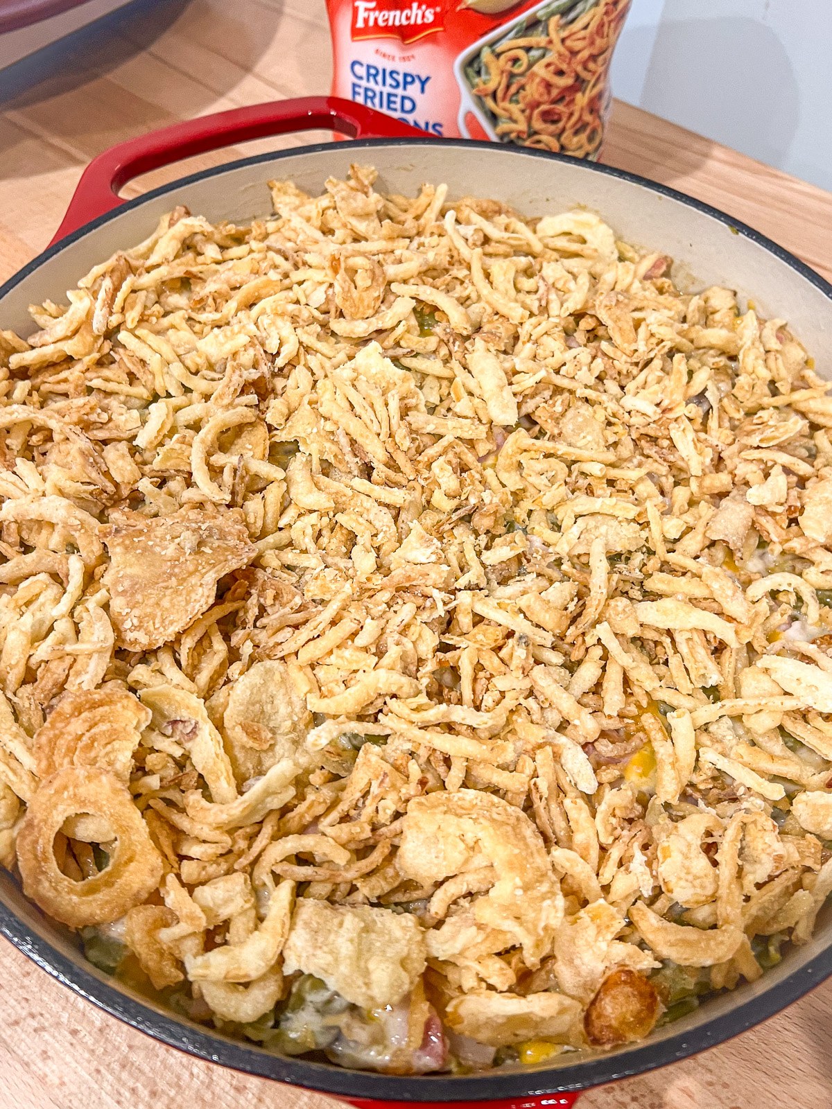 Assembled bacon green bean casserole topped with crispy fried onions before baking.
