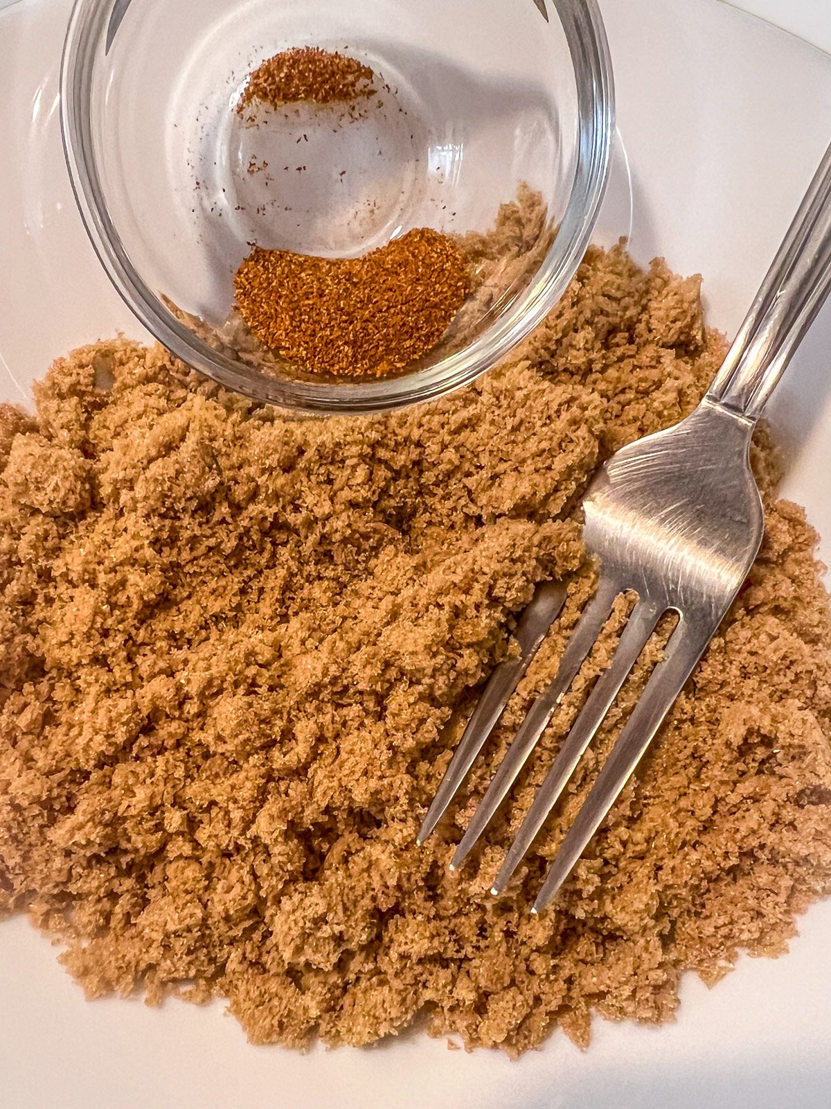 Brown sugar and cayenne pepper combined in a glass bowl.