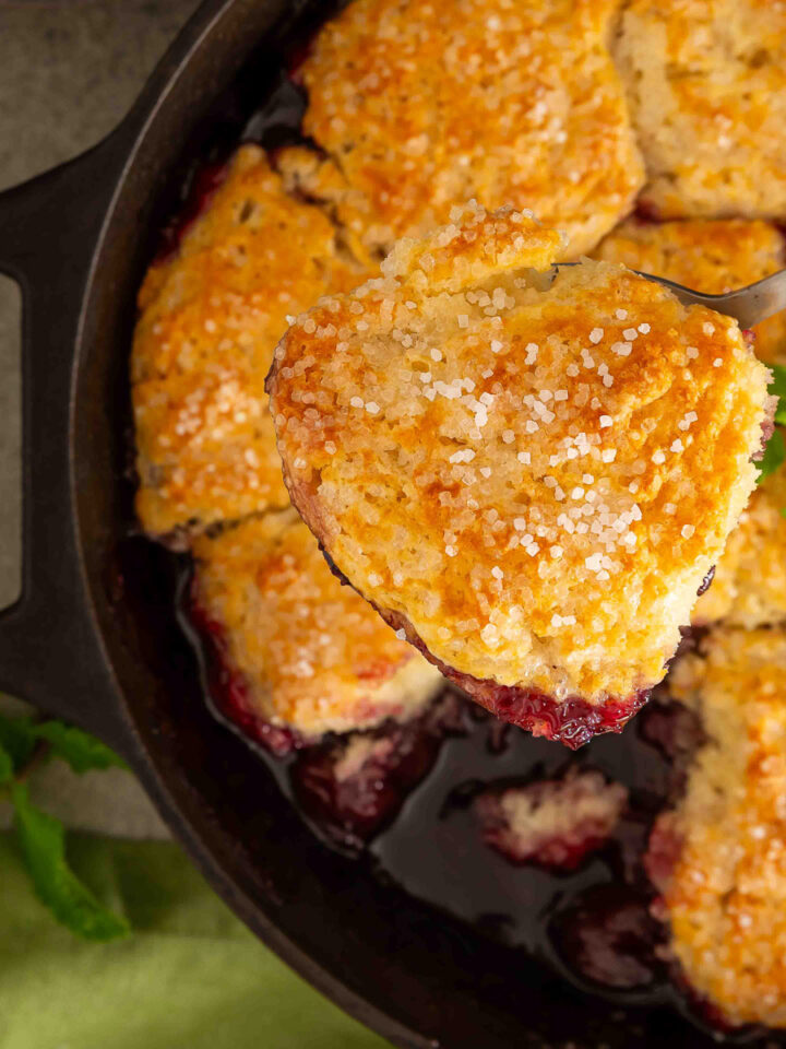 Cast iron cherry cobbler with a golden biscuit topping in a skillet