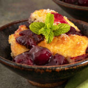 Bowl of cherry cobbler topped with vanilla ice cream and fresh mint