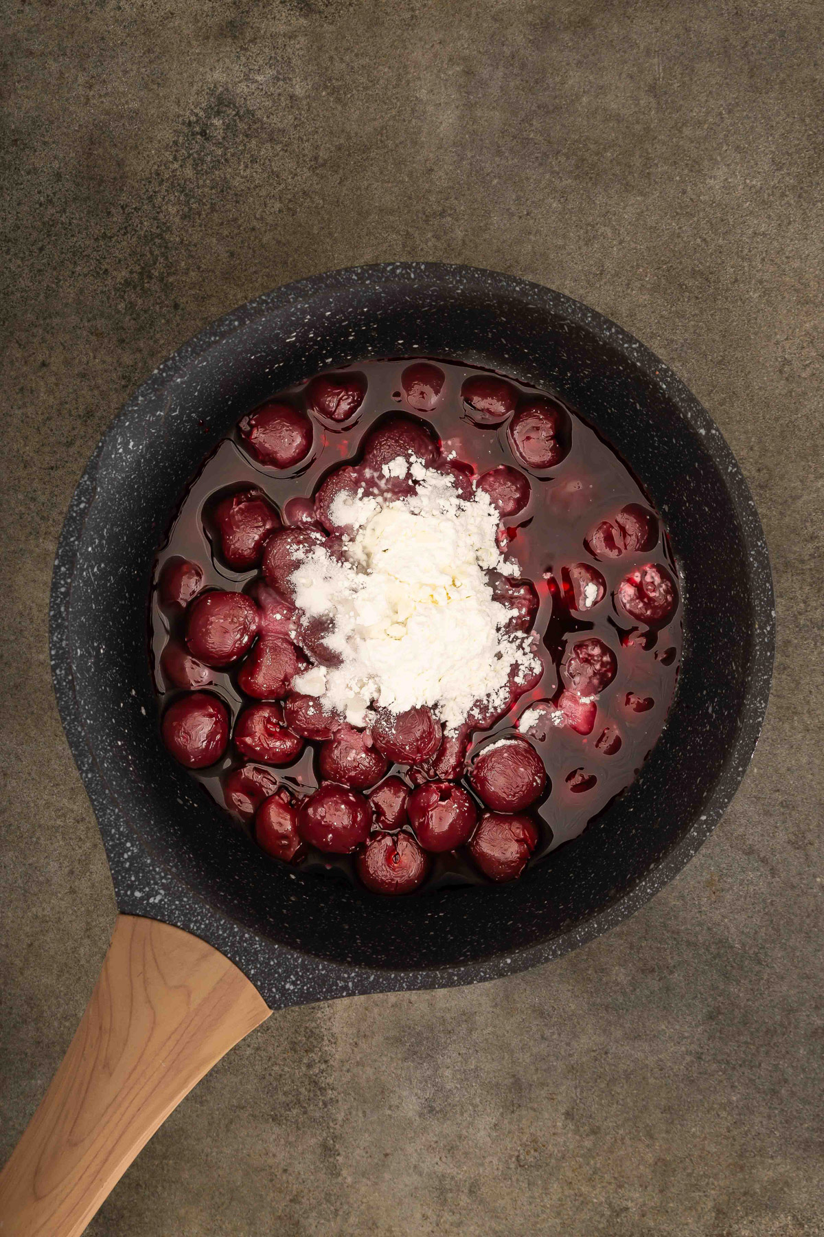 Drained canned cherries with sugar and cornstarch in a skillet