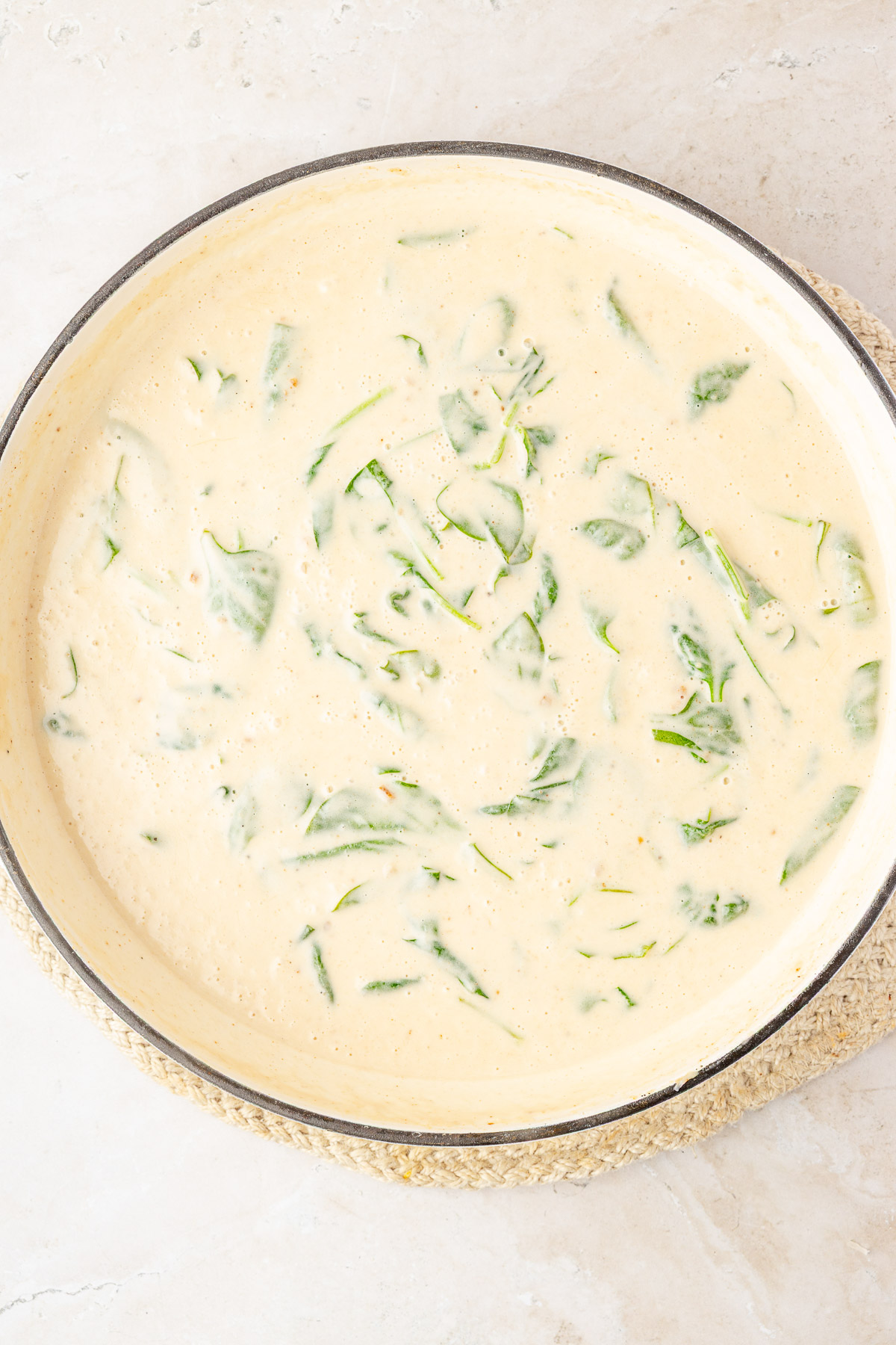 Baby spinach wilting into the creamy Parmesan sauce