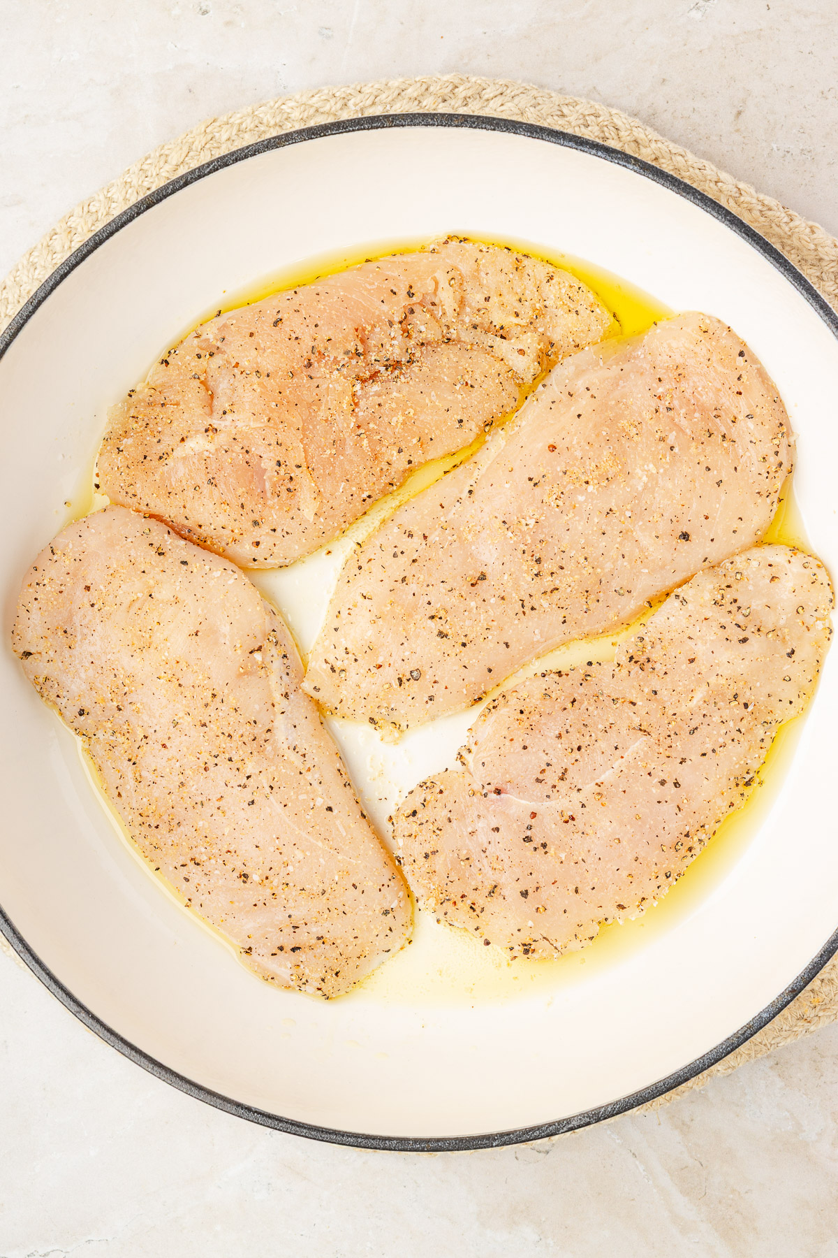 Seasoned chicken cutlets on a plate before searing