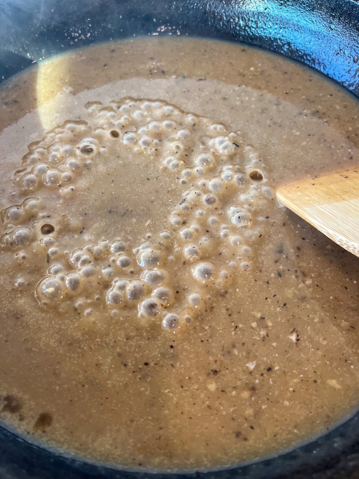 Gravy coming to a boil in the skillet.
