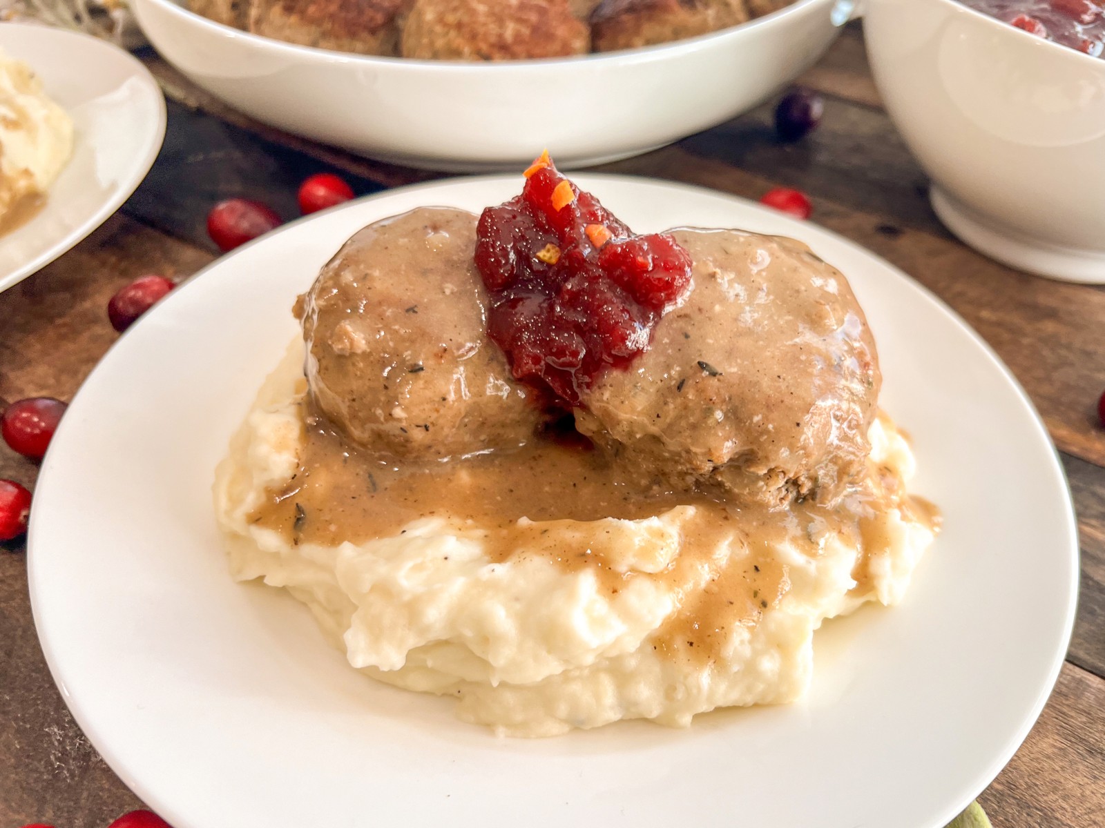Gravy served over mashed potatoes and turkey and stuffing meatballs with cranberry sauce.