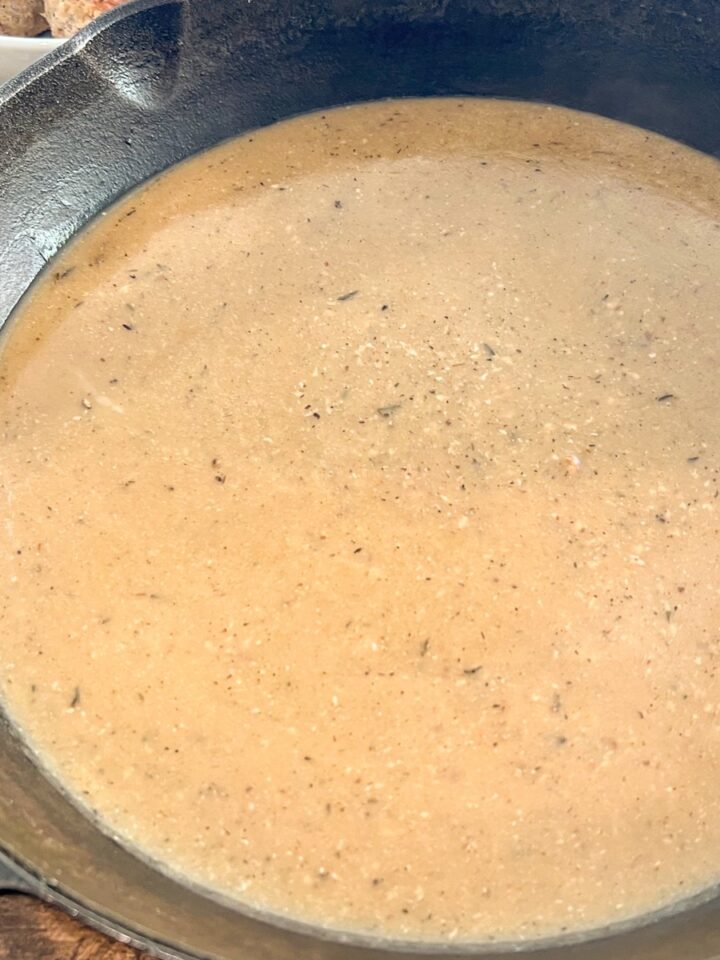 Pan gravy in a cast iron skillet is done and ready to be served.