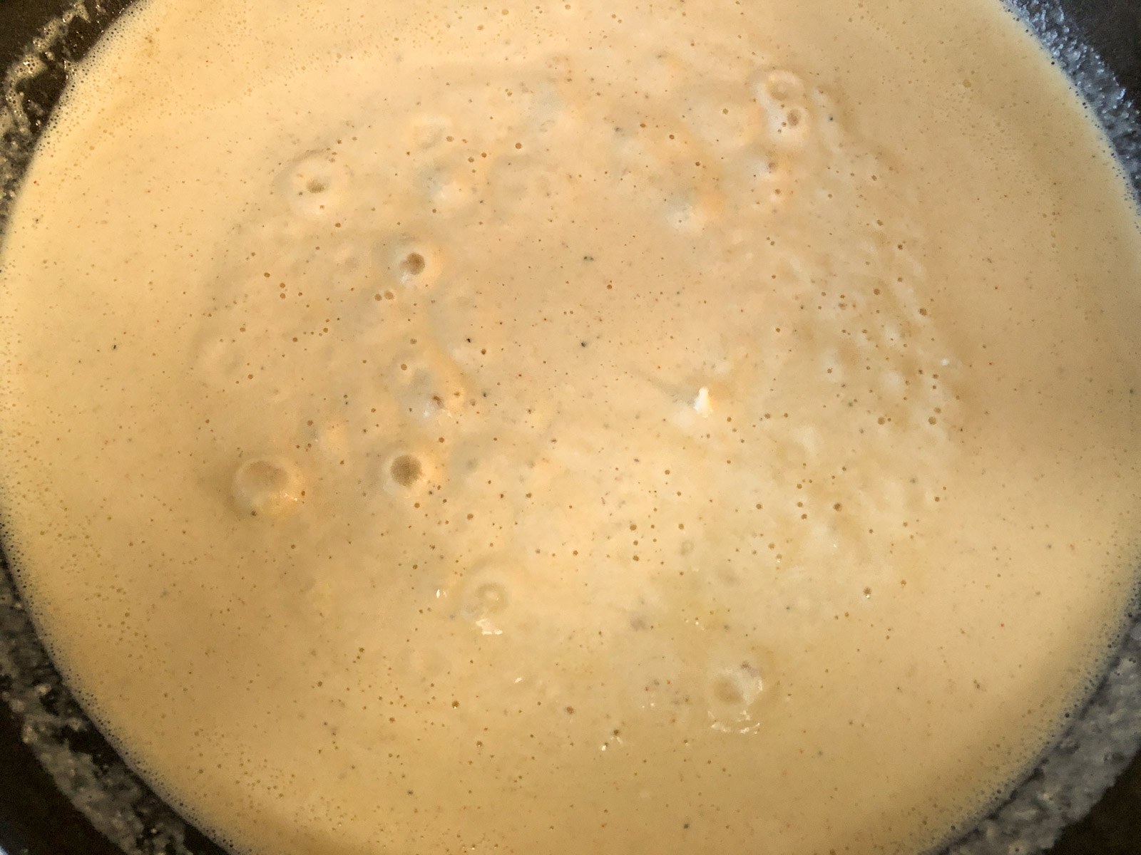 Creamy custard cheese sauce base melting in a cast iron skillet