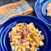 Creamy mac and cheese with ham served on a blue plate