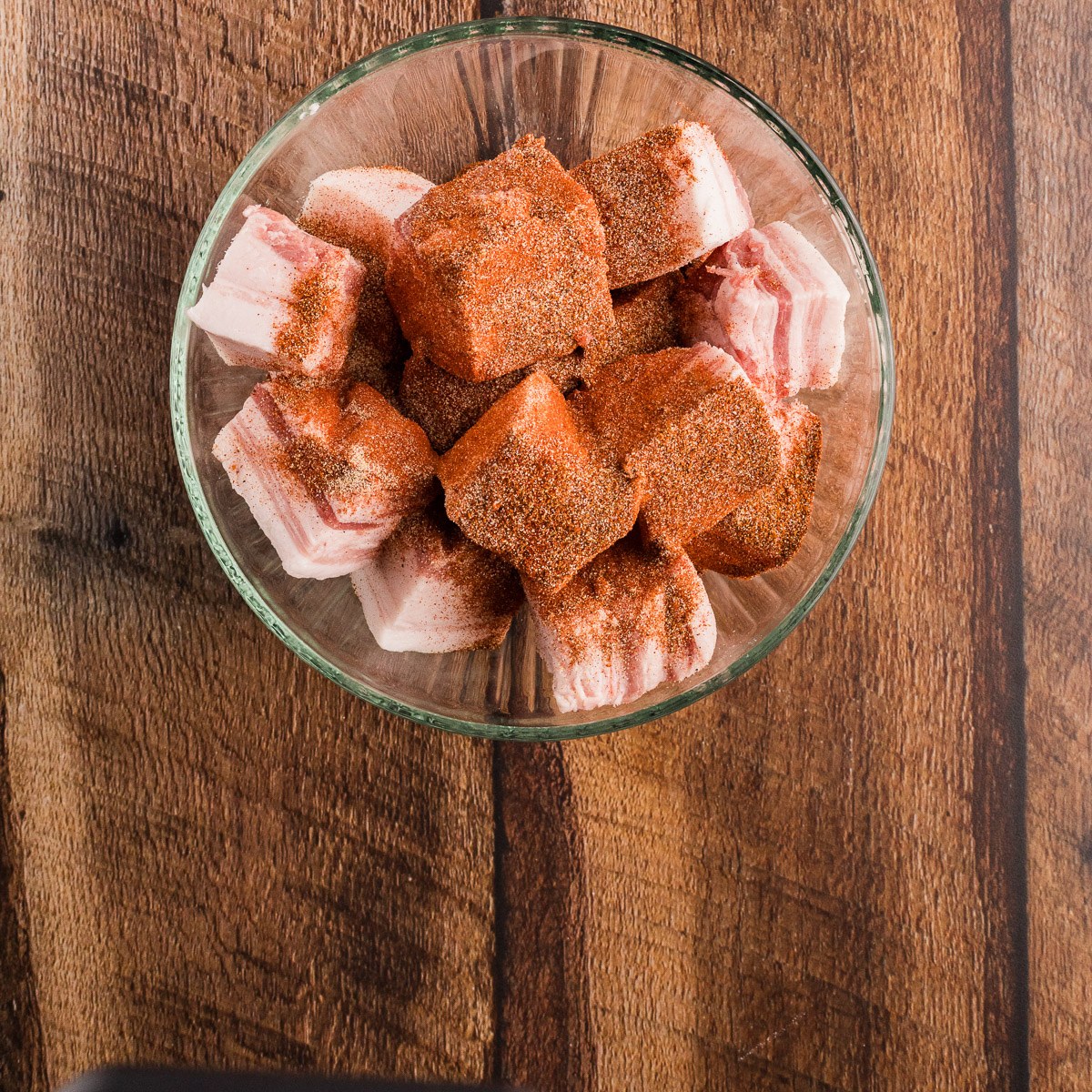 Cubed pork belly tossed in BBQ dry rub in a glass bowl