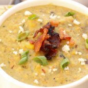 Roasted Poblano Corn Chowder in a white bowl garnished with bacon and queso fresco.