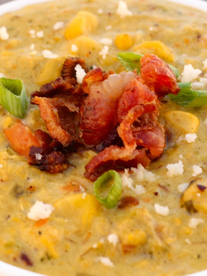 A bowl of Roasted Poblano Corn Chowder topped with bacon, queso fresco, and green onions.