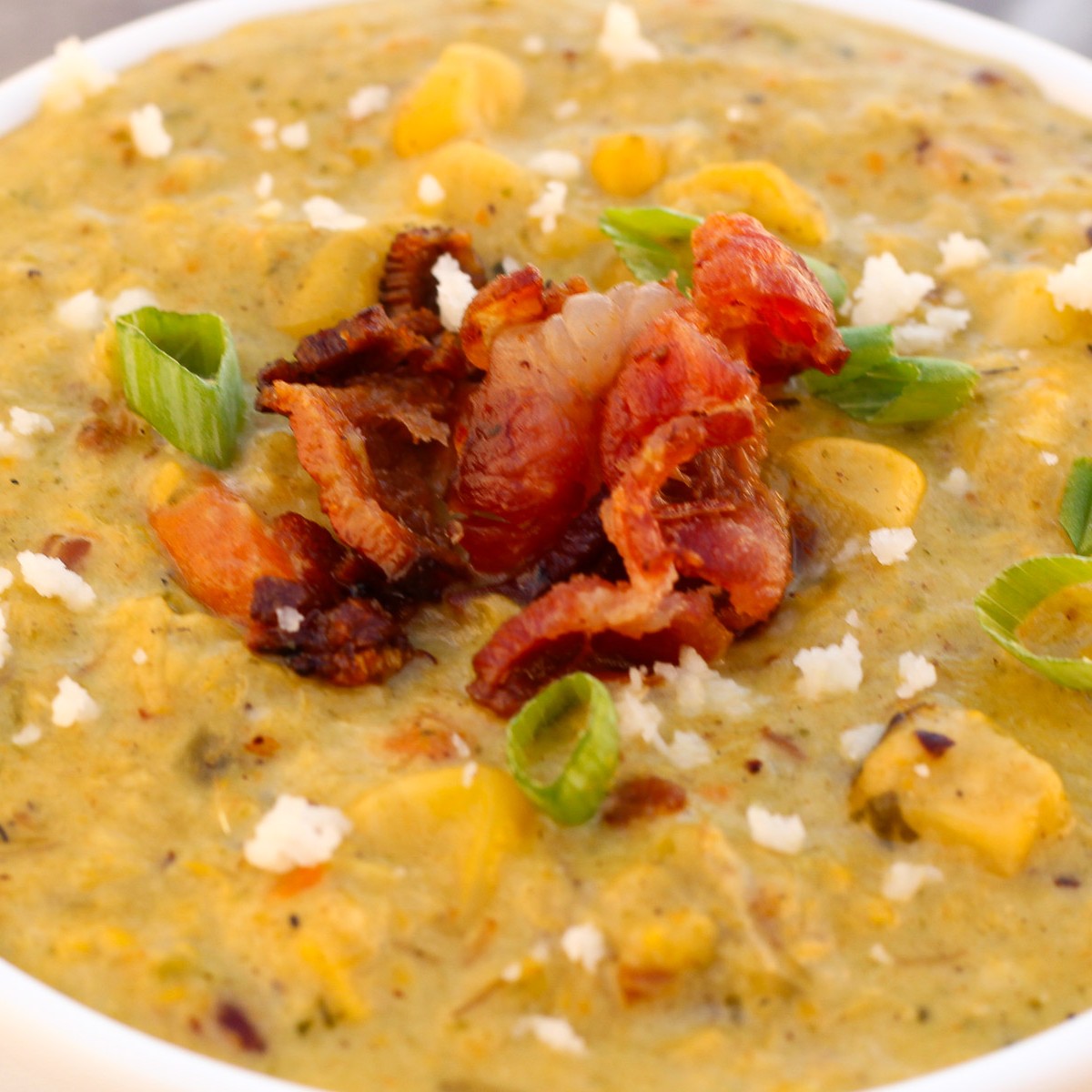 A bowl of Roasted Poblano Corn Chowder topped with bacon, queso fresco, and green onions.