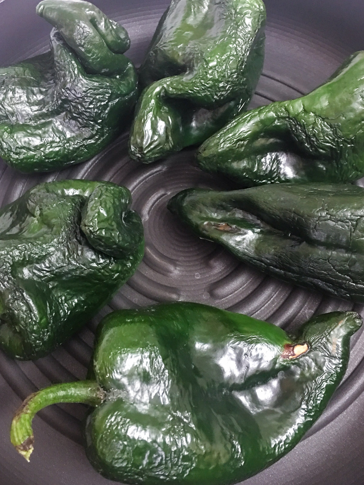 Poblano peppers blistered and blackened on the grill.