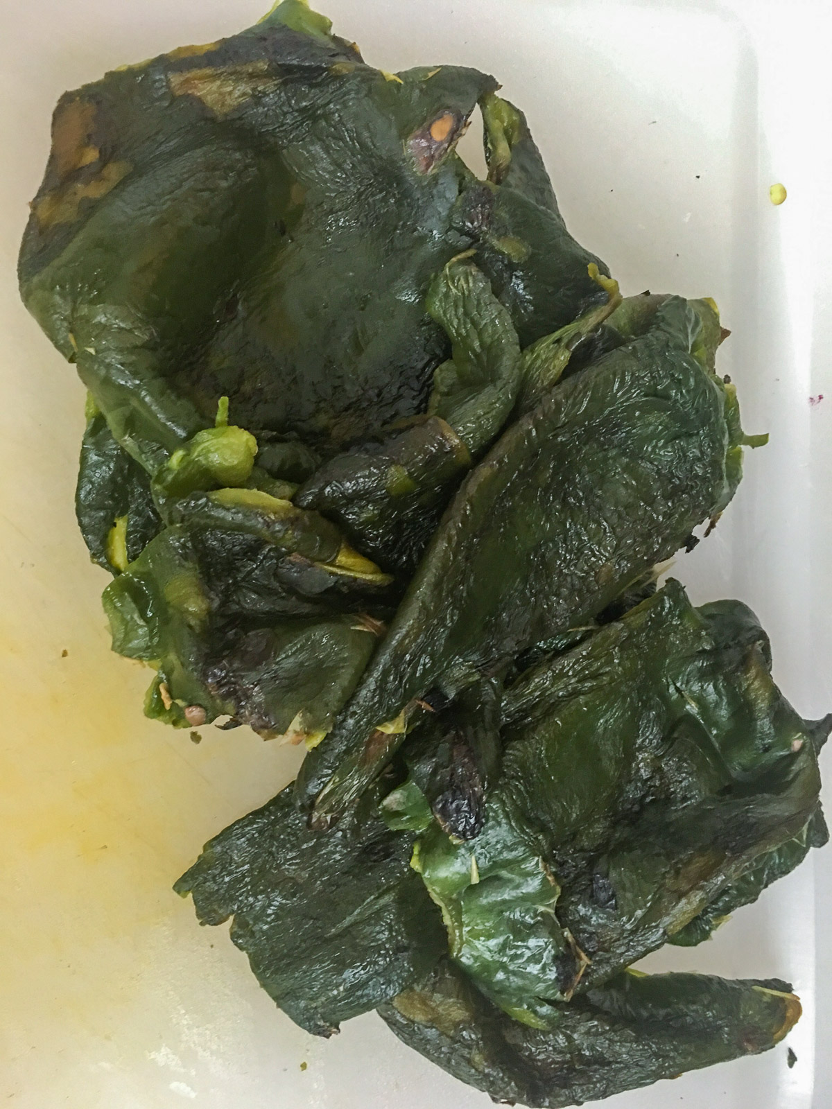 Charred skin being peeled off a roasted poblano pepper.