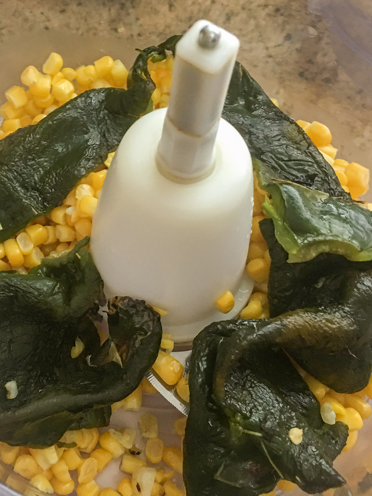 Reserved corn and poblano pureed with milk in a food processor.