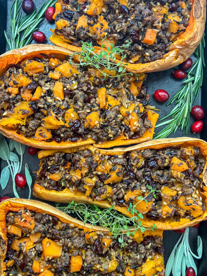 Sausage stuffed butternut squash halves in a cast iron pan.