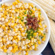 Bowl of southern creamed corn topped with chives and bacon crumbles.