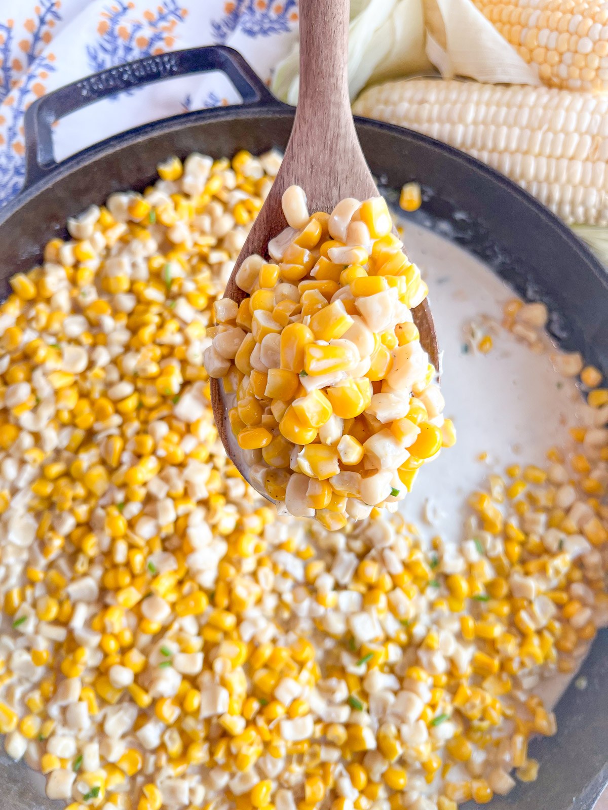 A spoonful of creamy southern creamed corn lifted from the cast iron skillet.