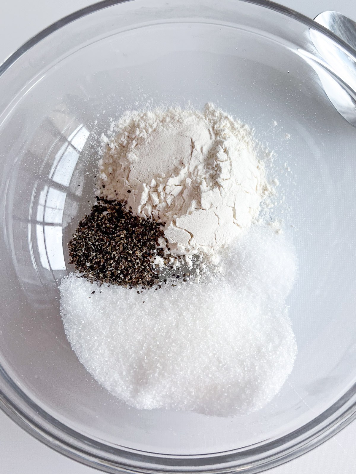 Flour, sugar, salt, and black pepper in a small bowl.