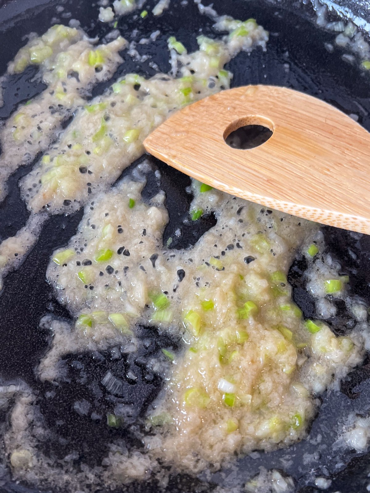 Minced onion sauteing in butter in a cast iron skillet.