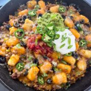 Loaded totchos in a cast iron skillet with guacamole, sour cream, salsa, and jalapenos.