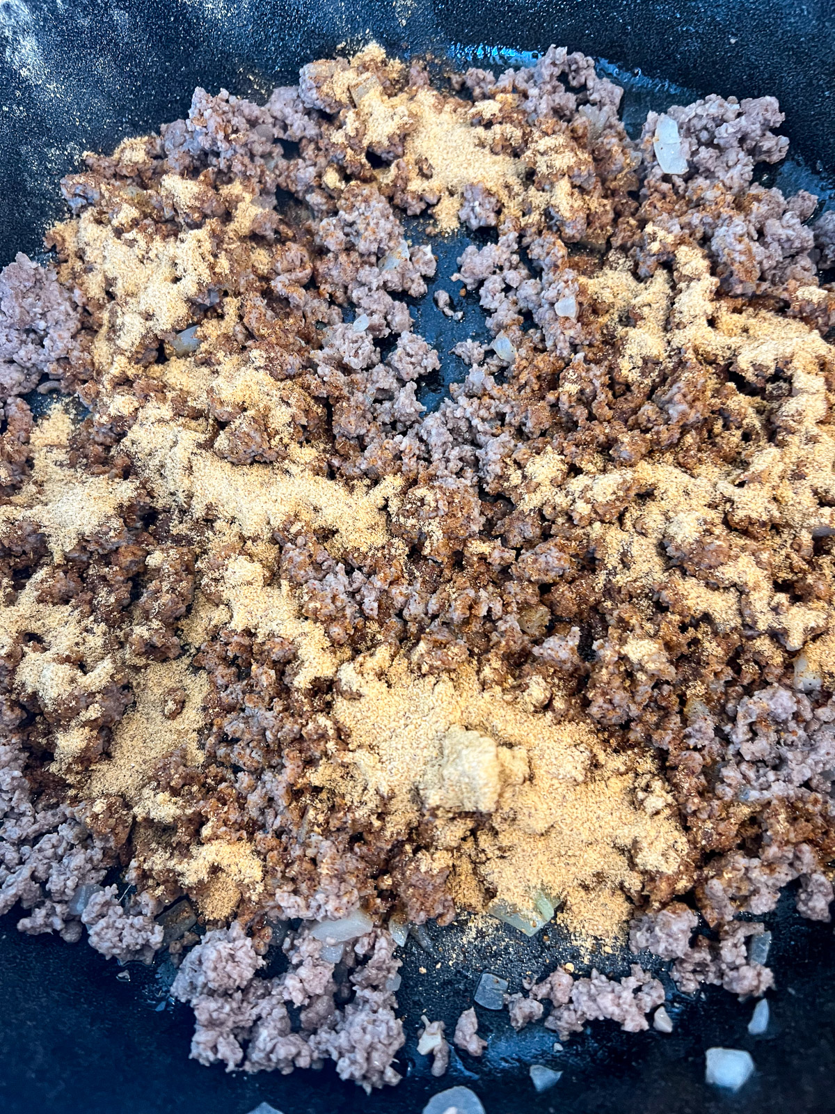 Taco-seasoned ground beef cooked in a skillet.