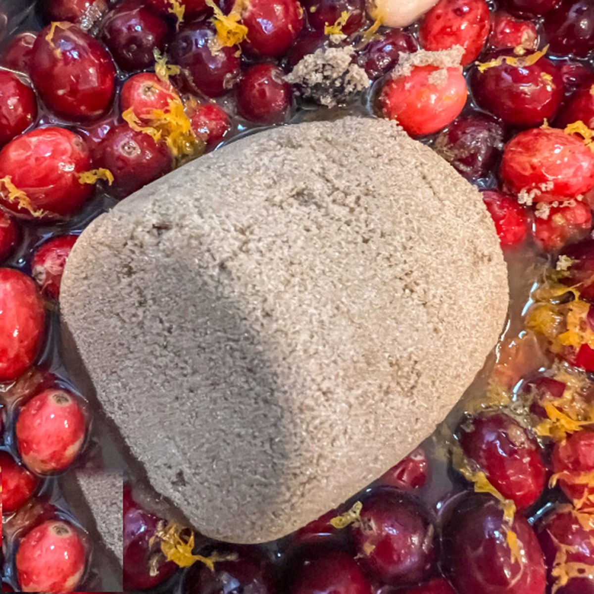 Dark brown sugar added to the cranberries and orange in the Dutch oven.