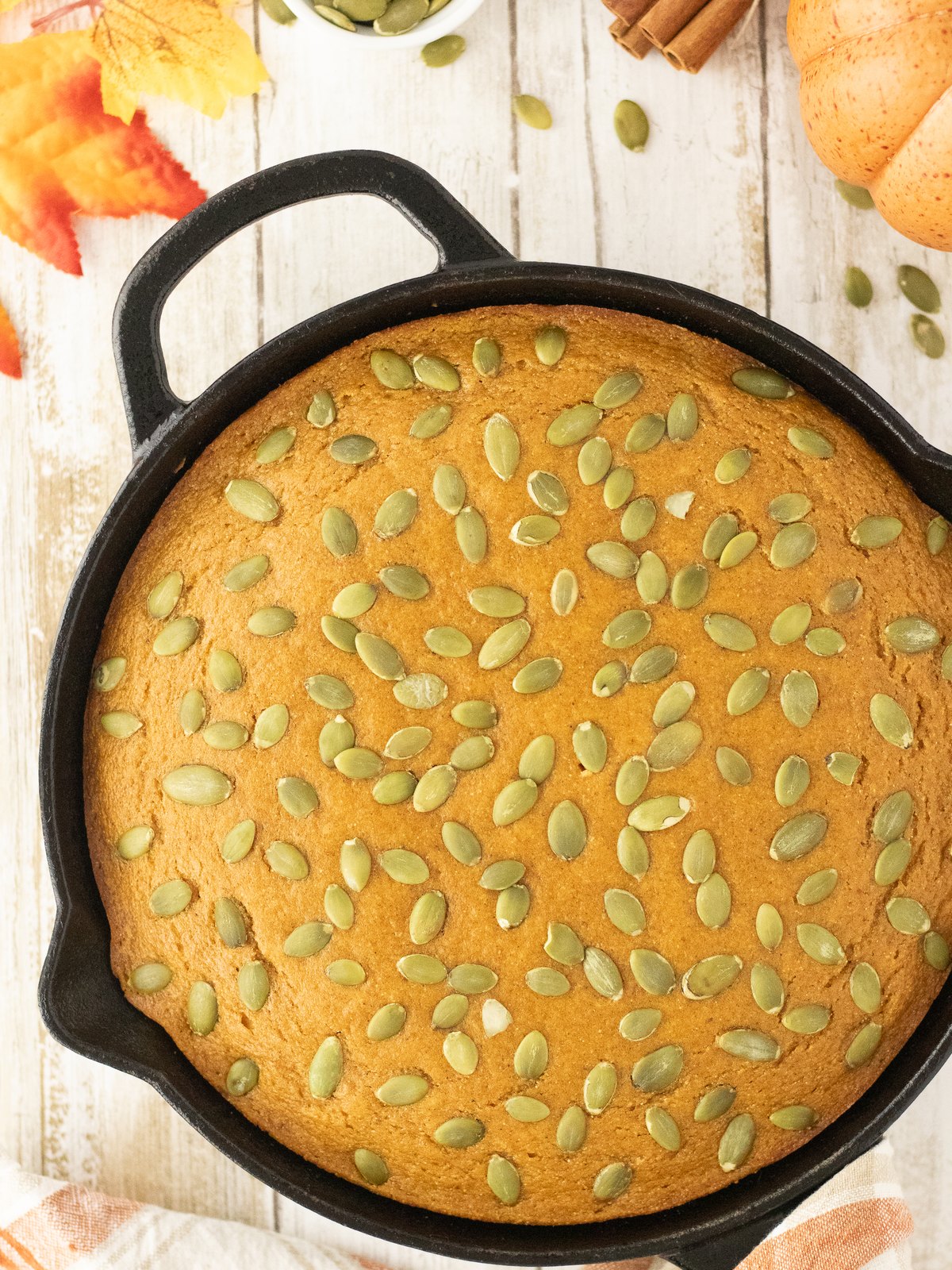 Pumpkin cornbread topped with pepitas baked in a black cast iron skillet
