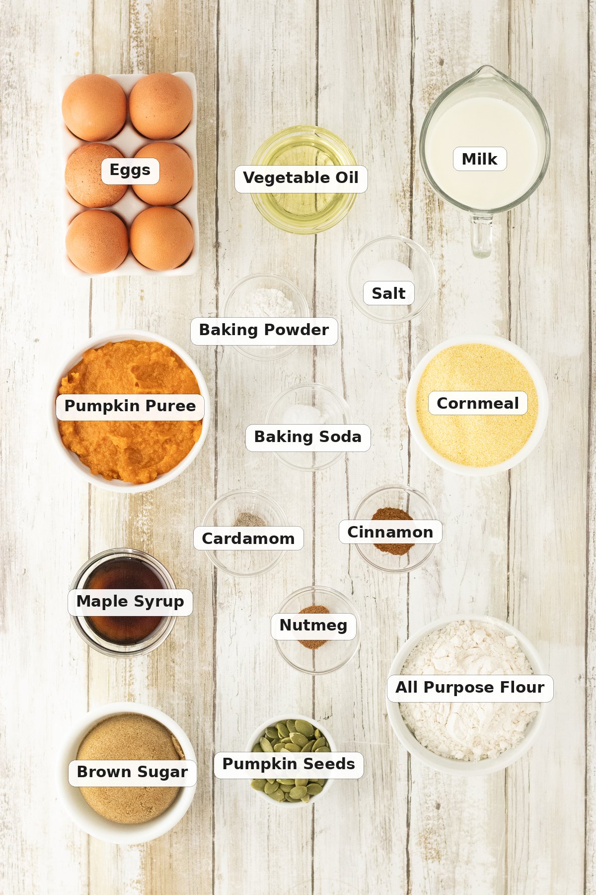 Labeled ingredients for pumpkin cornbread including cornmeal, flour, pumpkin puree, maple syrup and pepitas