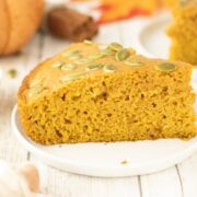 A slice of pumpkin cornbread on a white plate topped with pumpkin seeds