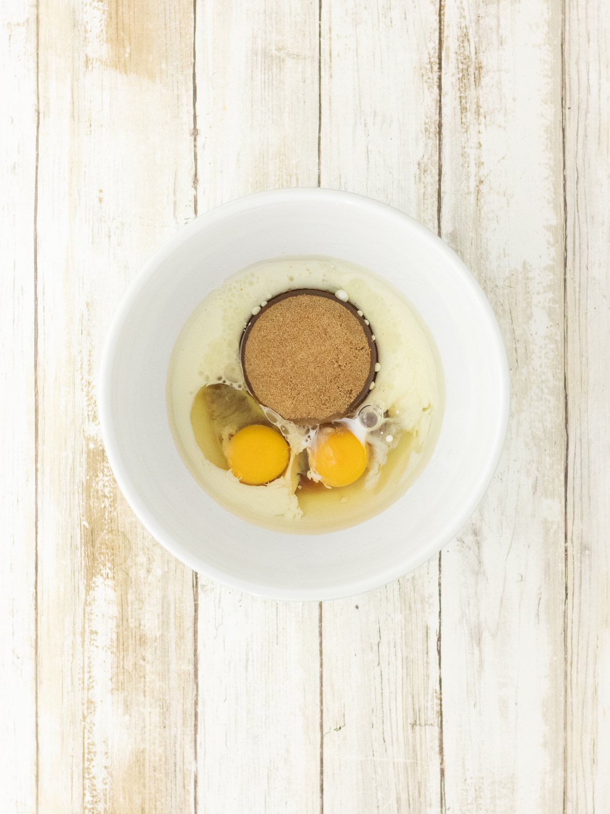 Eggs, oil, milk, brown sugar and maple syrup whisked in a mixing bowl