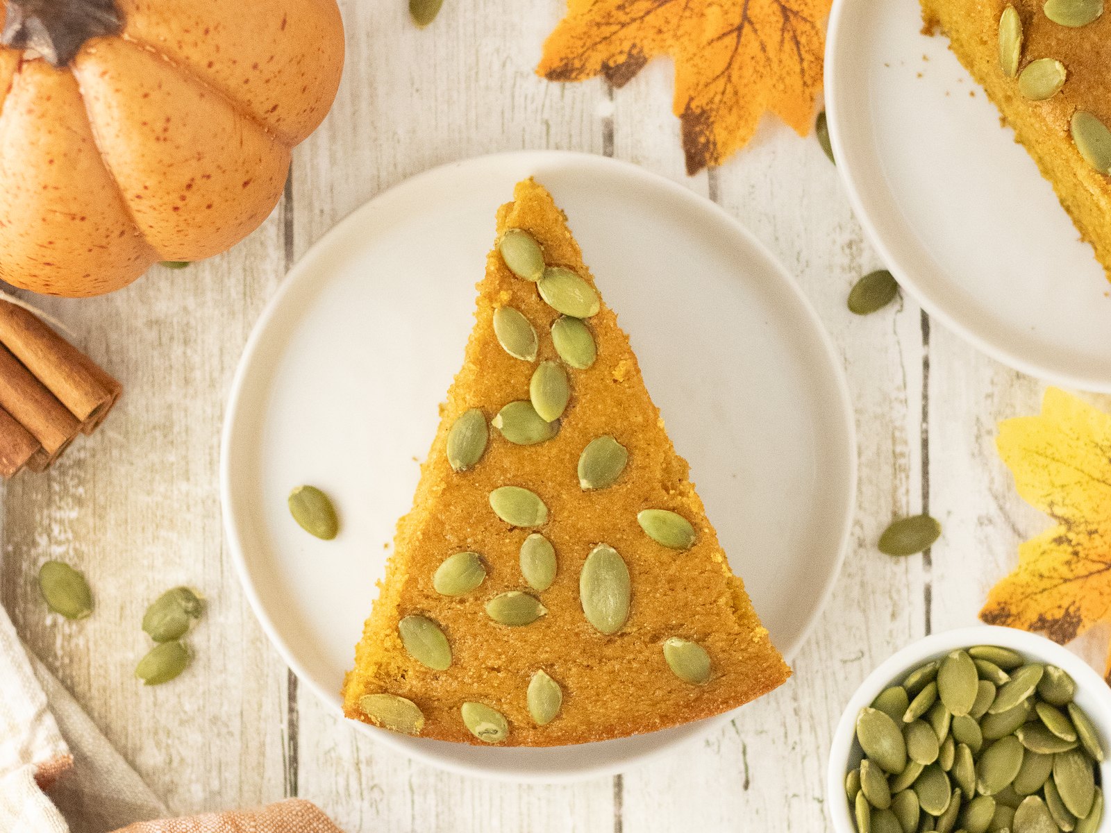 A slice of pumpkin cornbread on a white plate with autumn styling