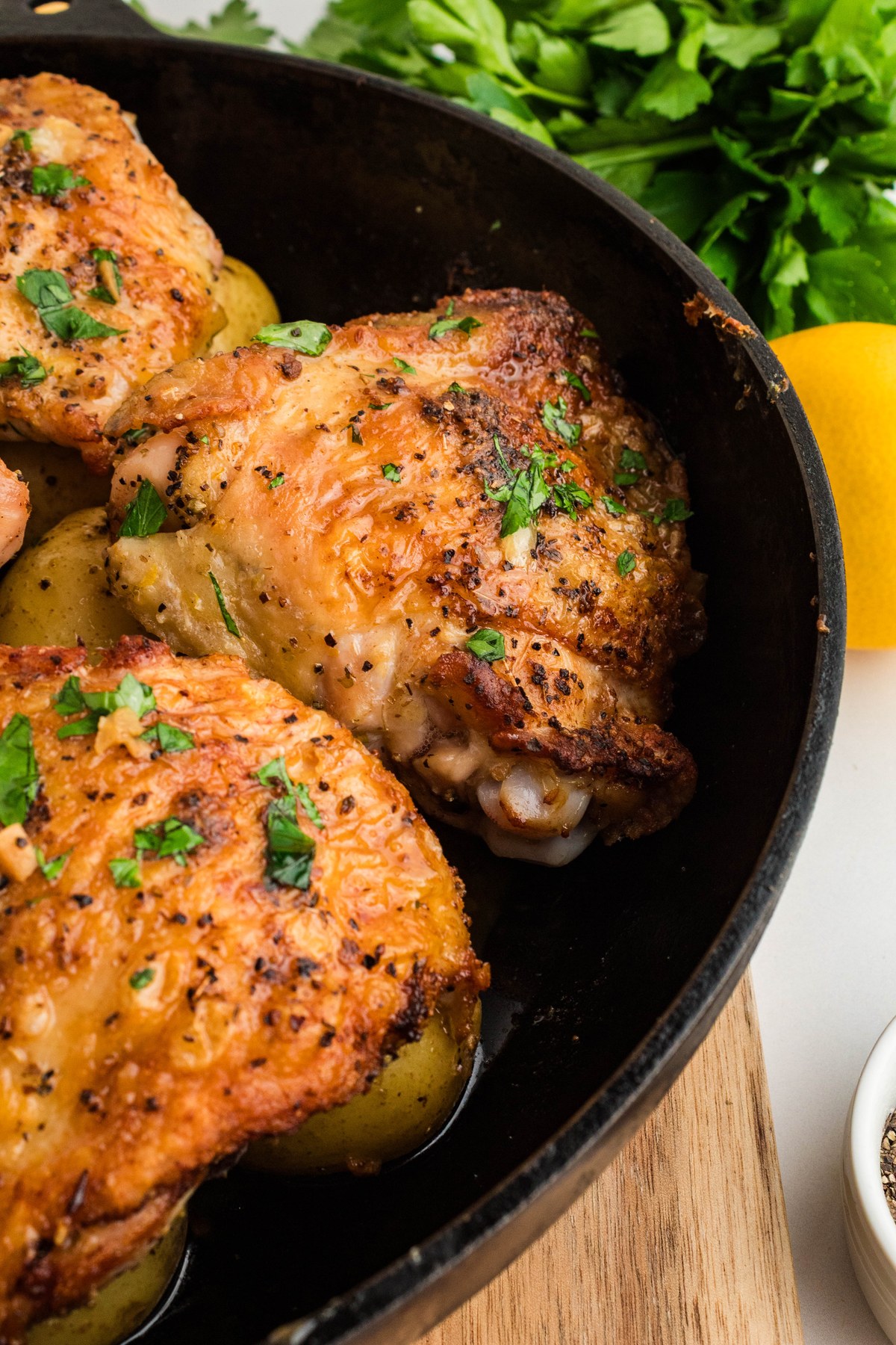Golden Greek lemon chicken and potatoes in a cast iron skillet with fresh parsley