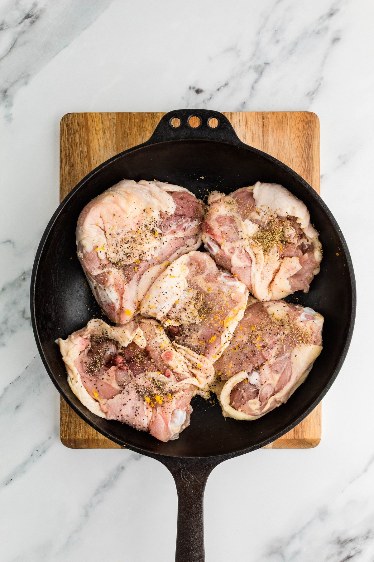 Chicken thighs searing skin side down in a cast iron skillet