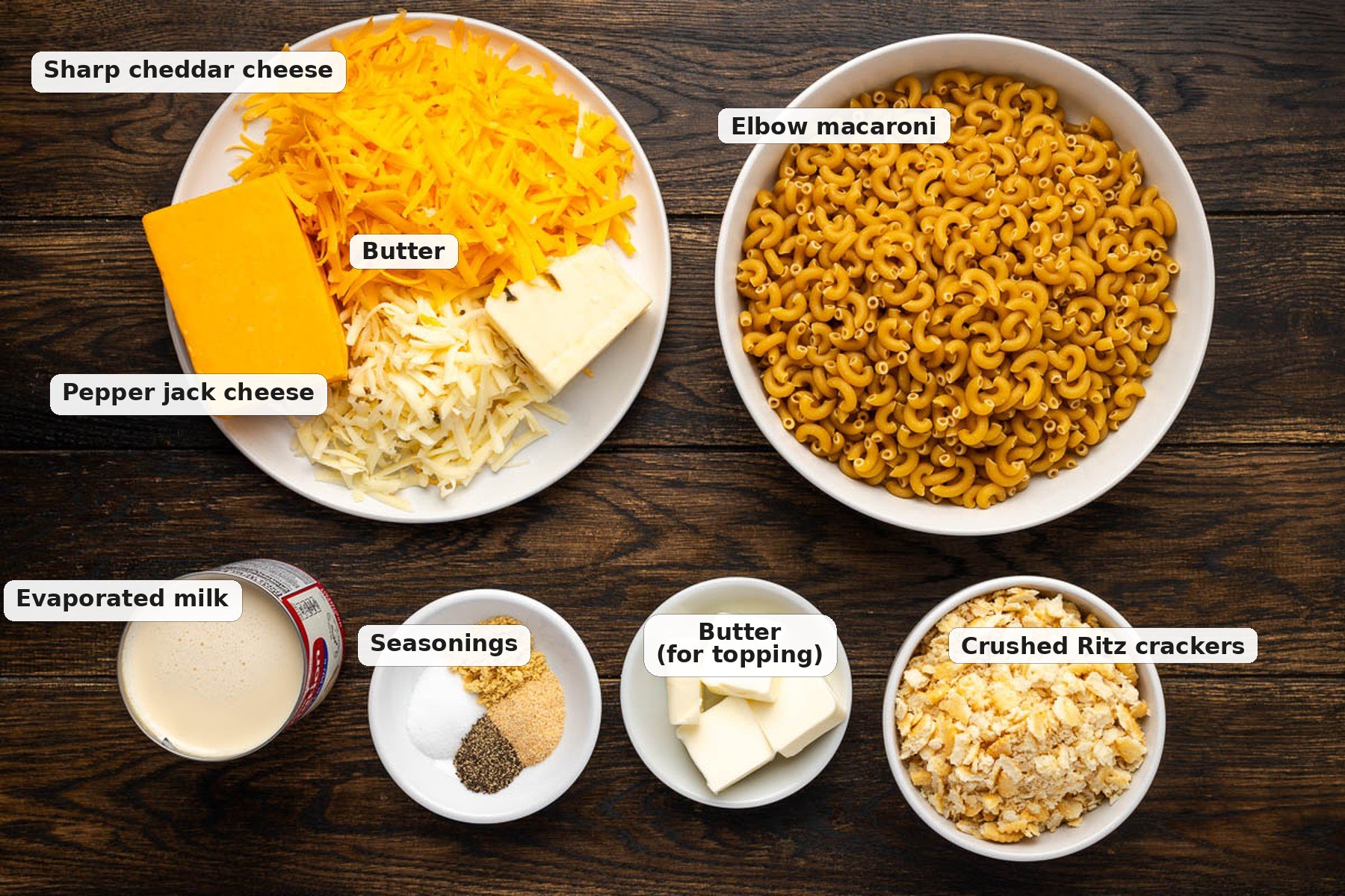 Labeled ingredients for dutch oven mac and cheese including elbow macaroni sharp cheddar pepper jack butter evaporated milk and Ritz crackers