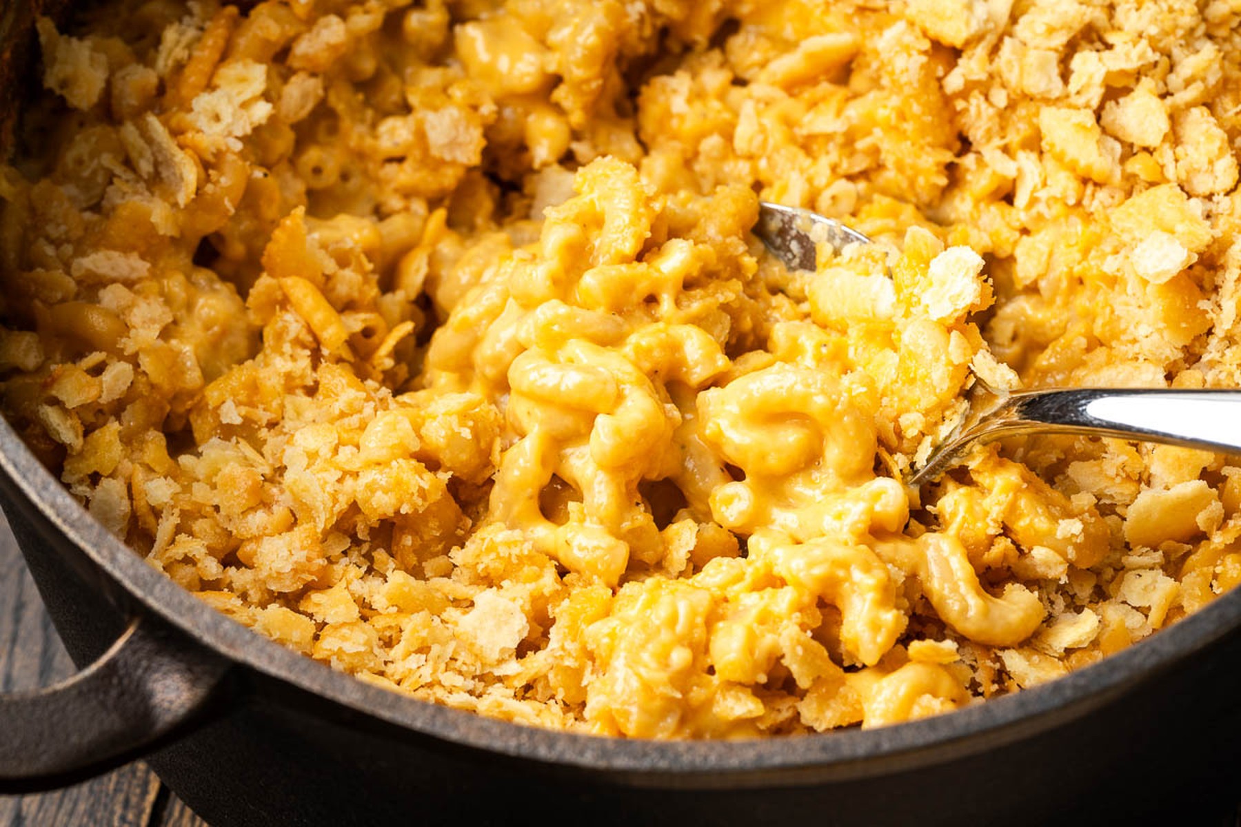 Spoon lifting a scoop of creamy cheesy pasta with cracker crust