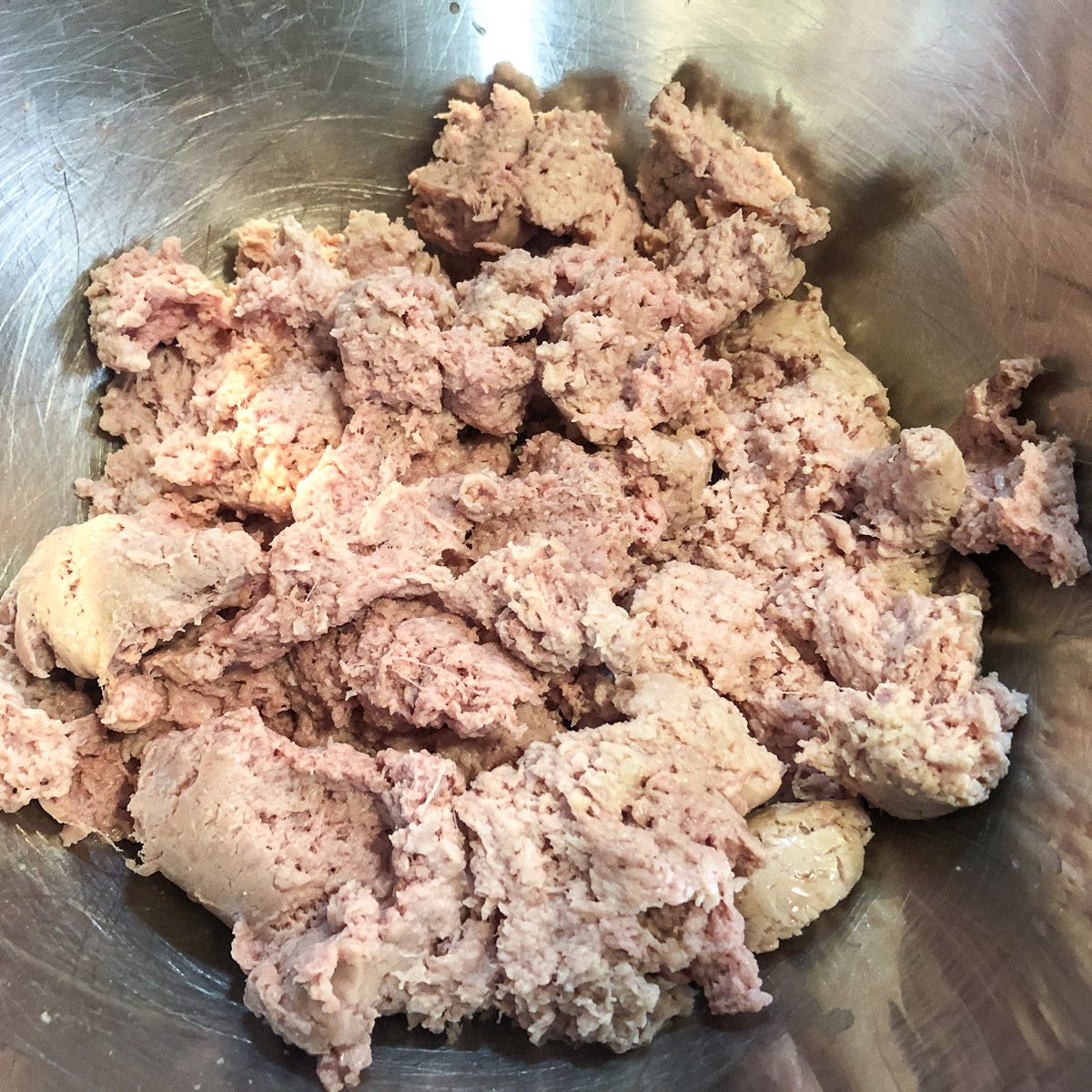 Ground turkey and ground sausage in a stainless steel mixing bowl.