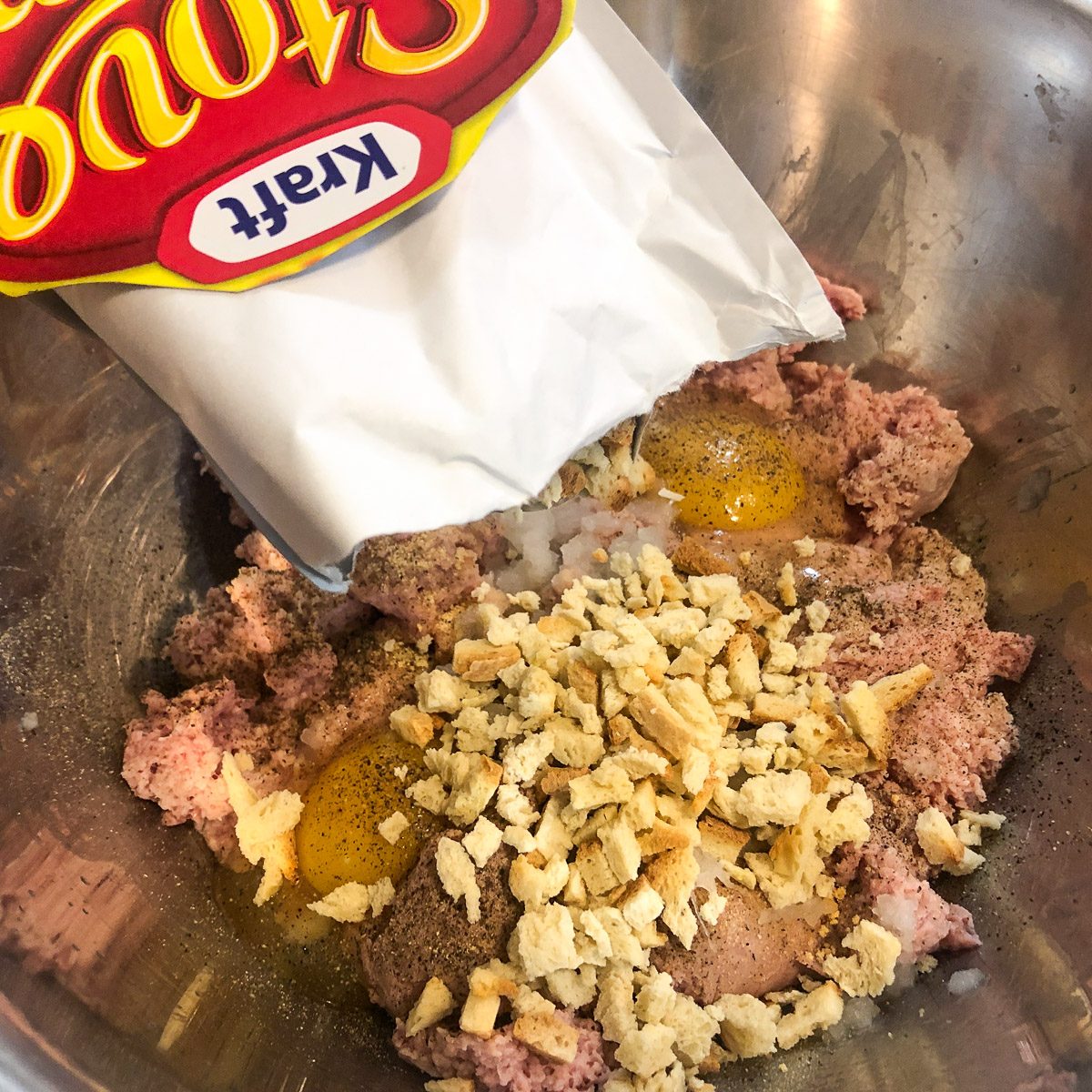 Stove Top stuffing mix being poured into the seasoned meat mixture.
