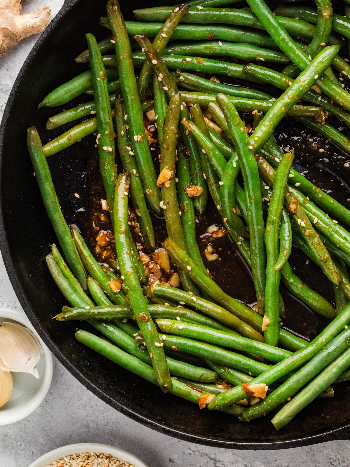 Overhead view of glossy Asian green beans in a cast iron skillet