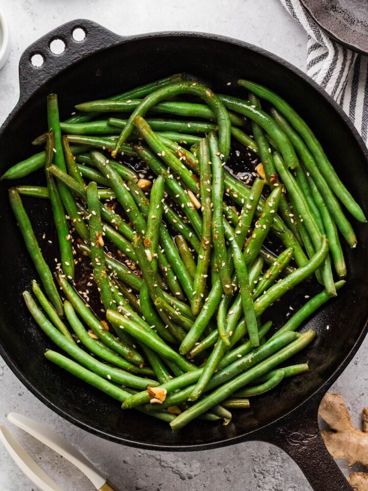 Asian green beans tossed in soy garlic sauce in a cast iron skillet