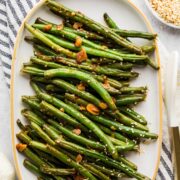 Asian green beans served on a white oval platter with sesame seeds