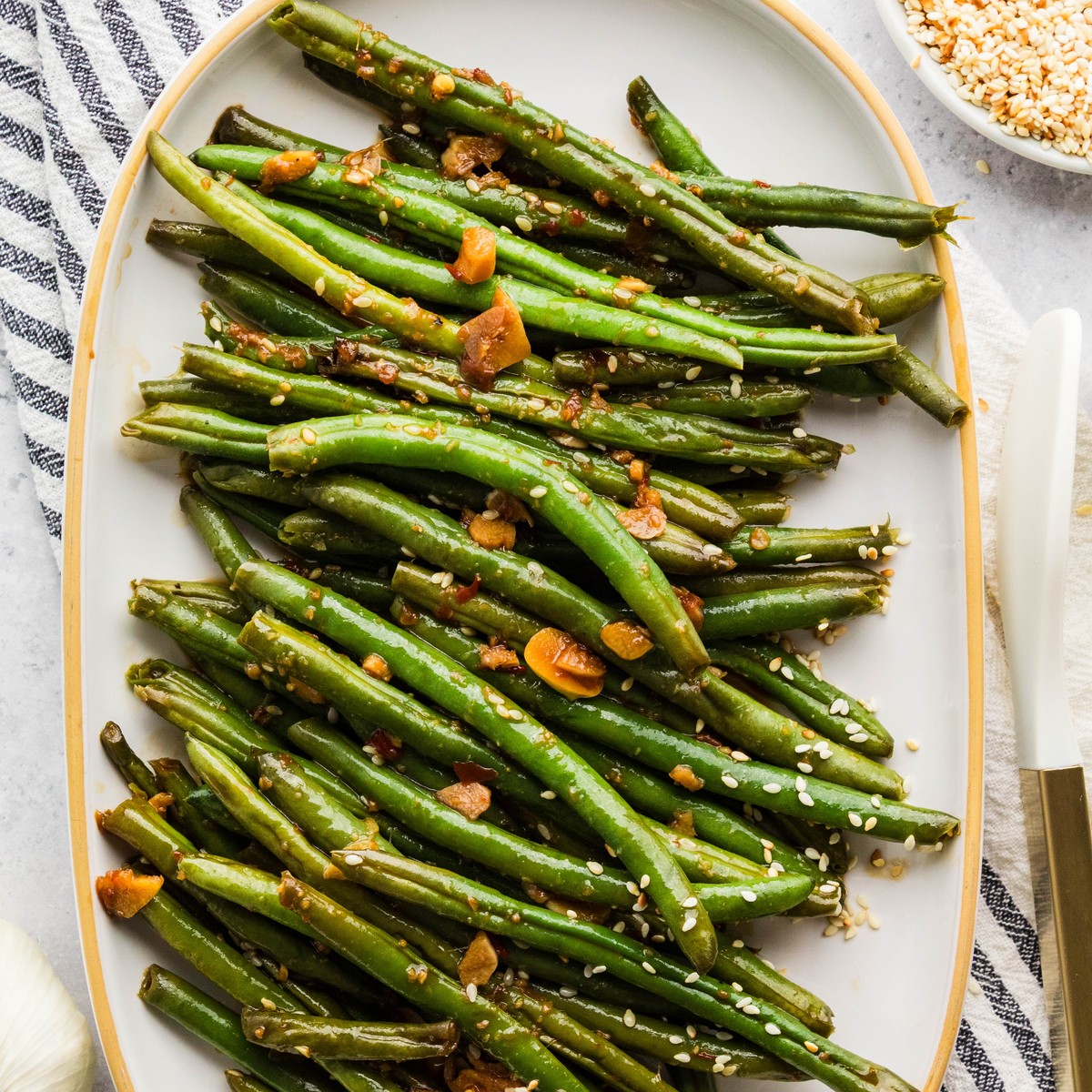 Asian green beans served on a white oval platter with sesame seeds
