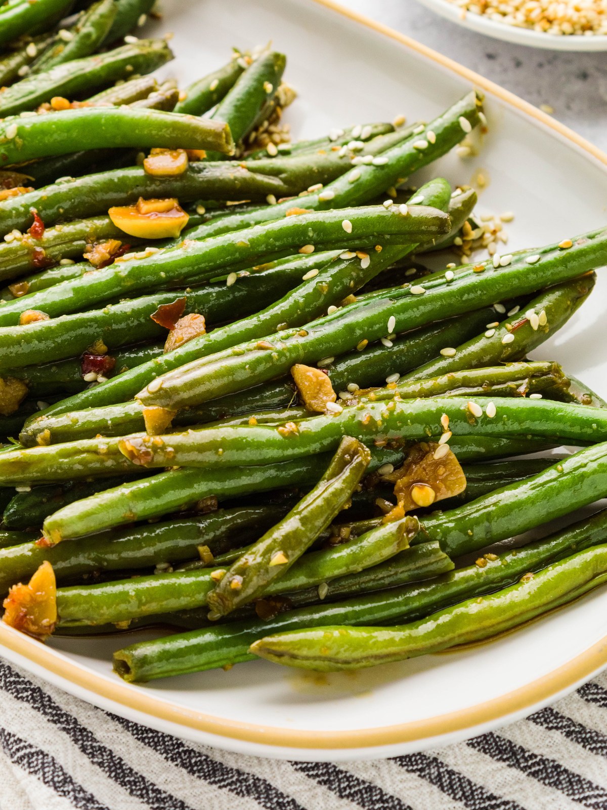 Asian green beans with garlic and sesame seeds on a white platter
