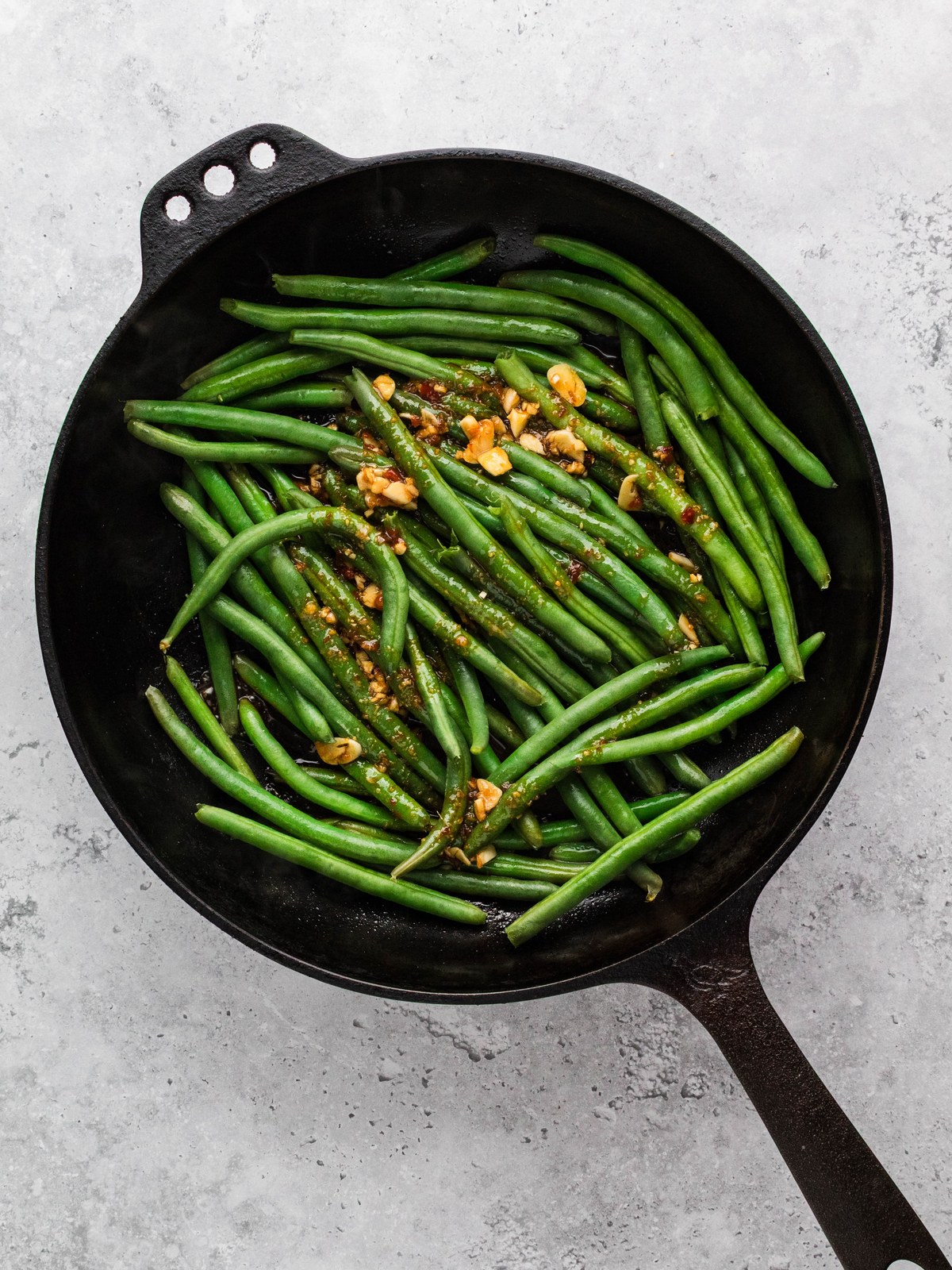 Fresh green beans steaming in a cast iron skillet